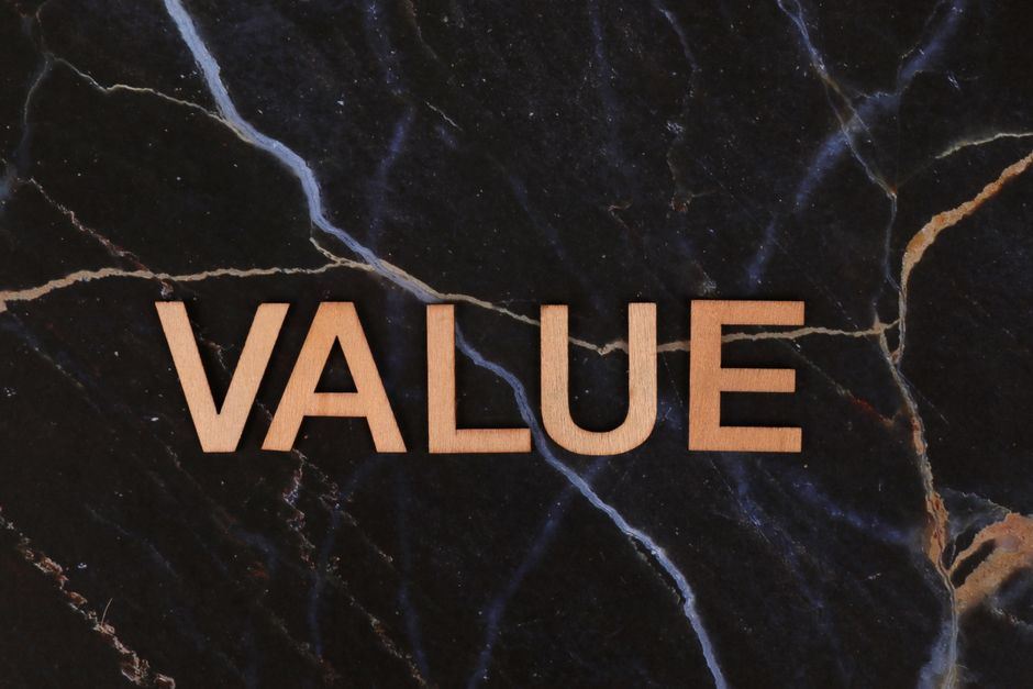 暗い大理石の背景に木製の「Value」の文字が配置され、質感とコンセプトが強調されているクローズアップ写真。
