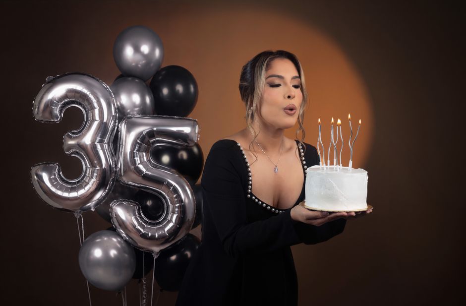 ケーキにろうそくを立て、風船で飾り付け、喜びと優雅さを表現しながら35歳の誕生日を祝う女性。