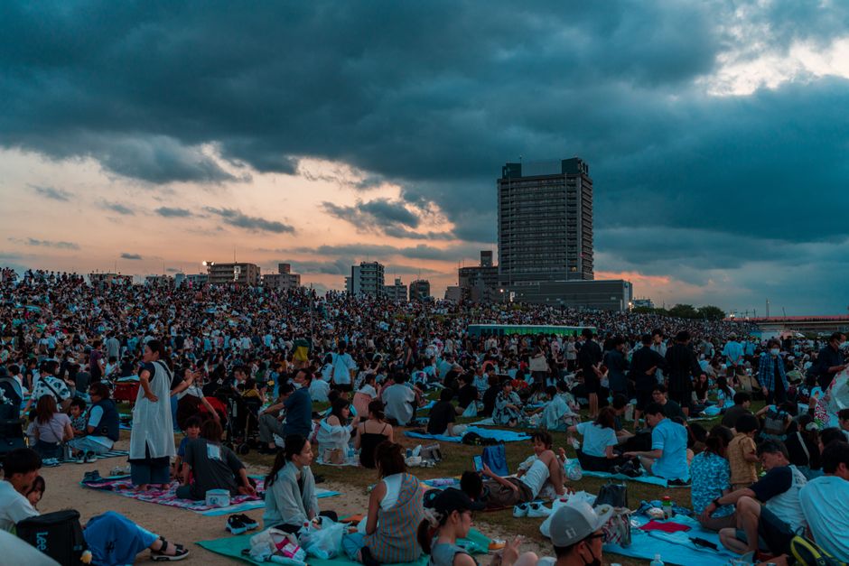 夕暮れのドラマチックな空の下、日本の東京で開催された夏祭りに大勢の人々が集まった。