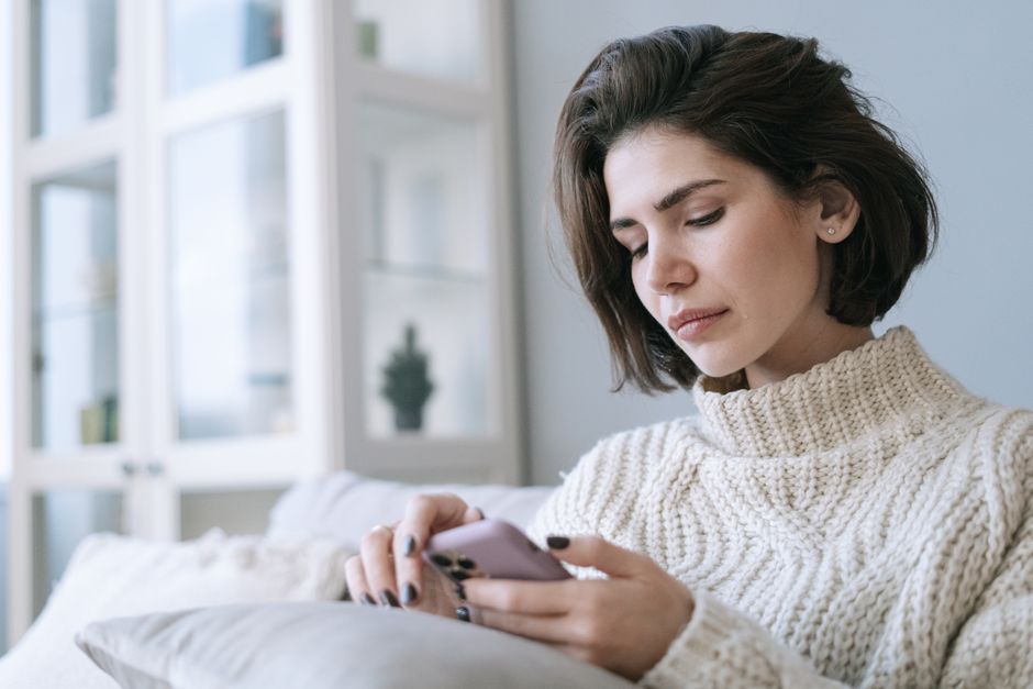 退職代行EXITに依頼後、上司からの連絡がなく自宅で落ち着いてスマートフォンを見る女性